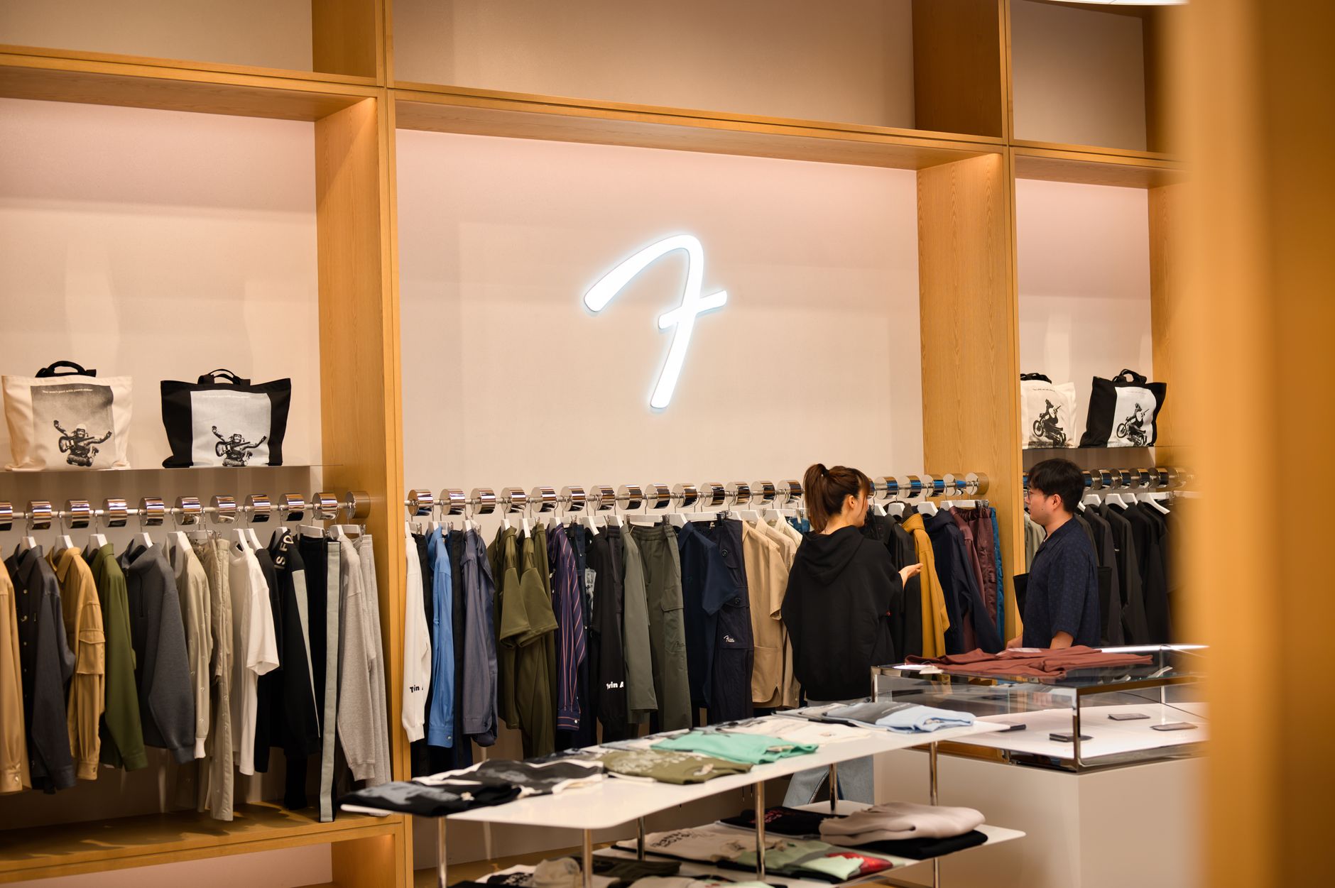 Interior of a stylish clothing store in Tokyo featuring two shoppers browsing modern apparel.