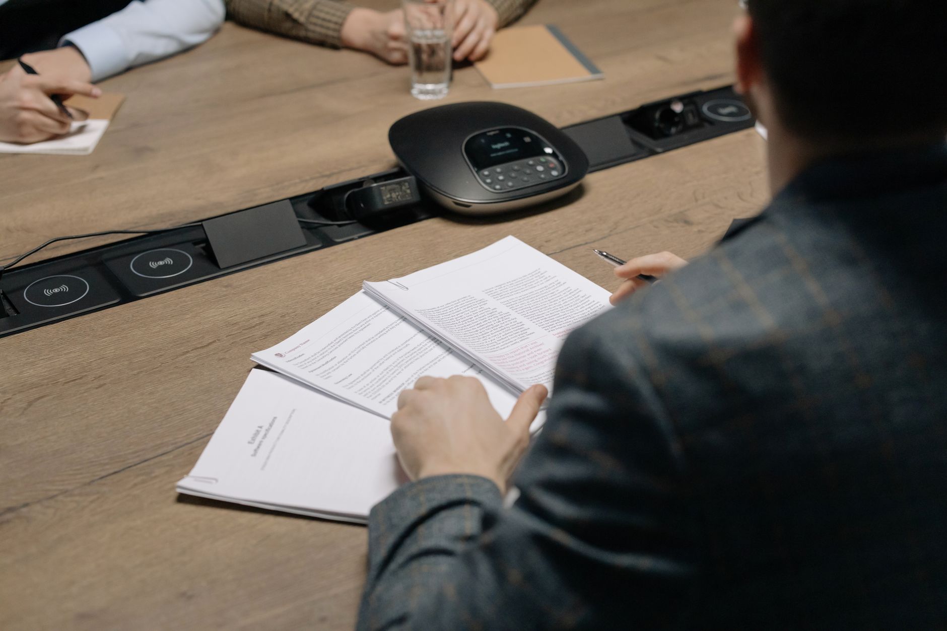 Close-up of business professionals reviewing documents during a meeting in a modern office setting.