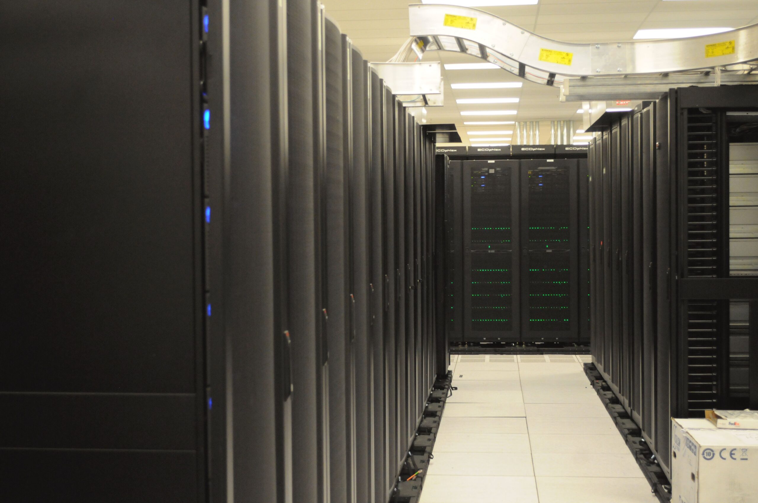 A data centre aisle between two rows of black server racks.